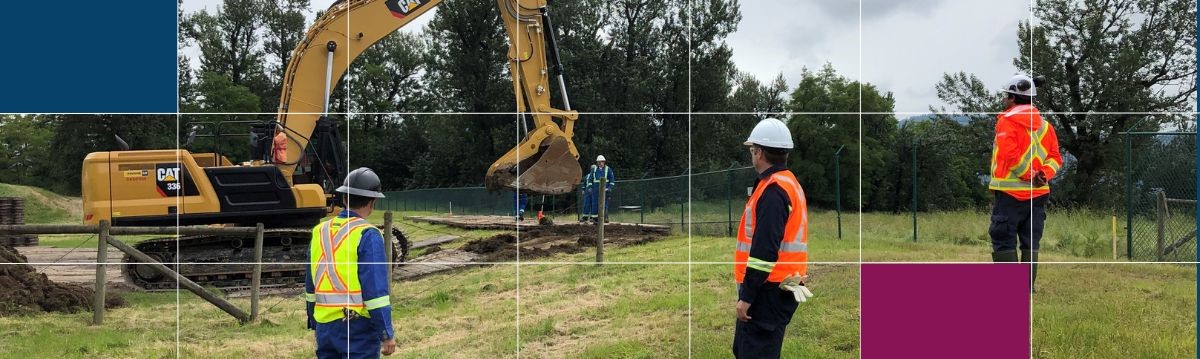 Quatre travailleurs de la construction dans un champ autour d’une pelleteuse. La photo se trouve derrière une grille blanche, une boîte bleu foncé et une boîte magenta.