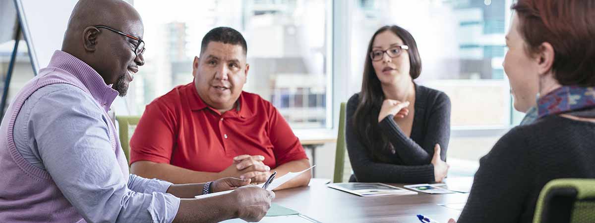 Four people sitting around a conference table in a meeting room