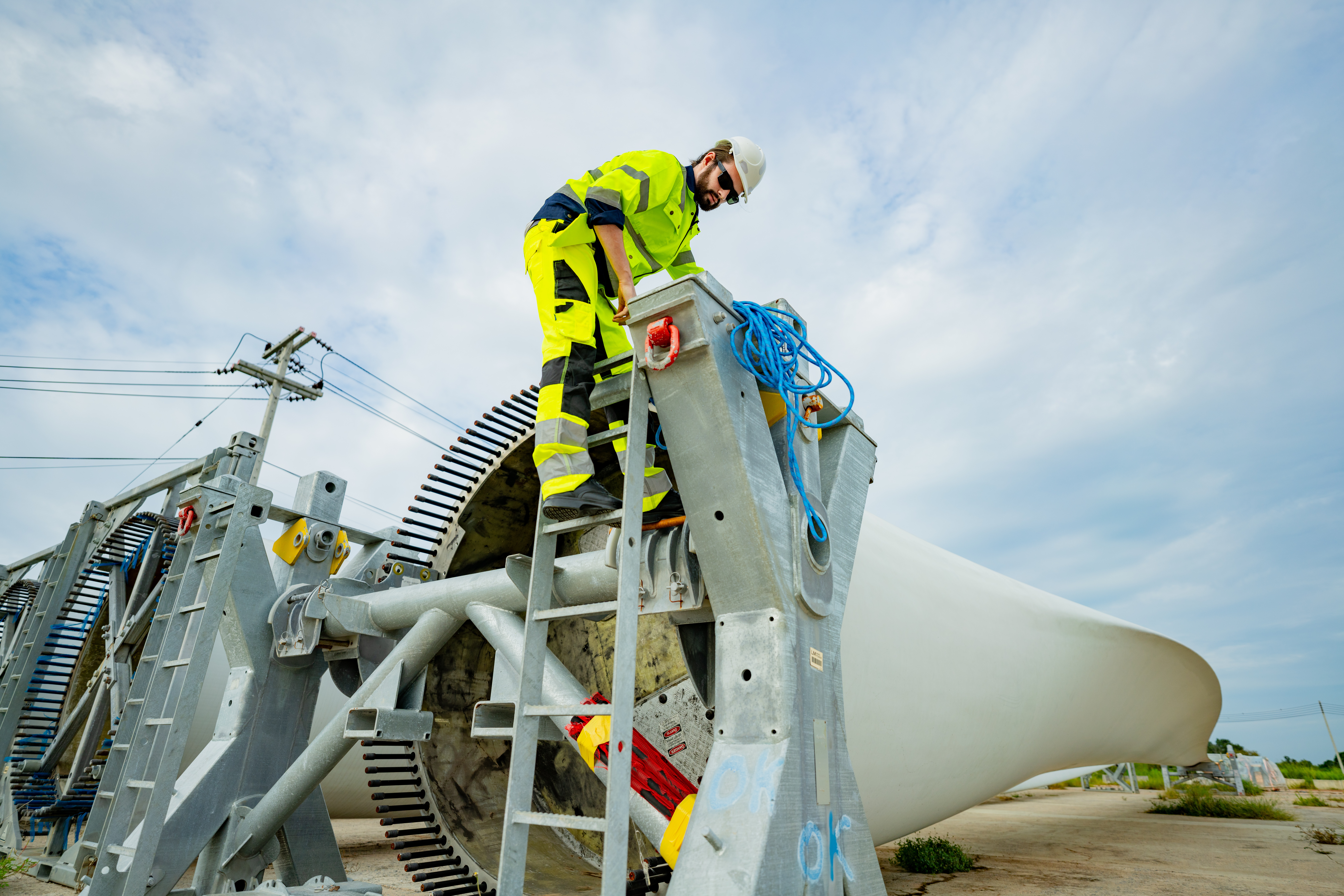 Un travailleur grimpe à l’échelle d’entretien pour inspecter une éolienne dans un parc éolien.