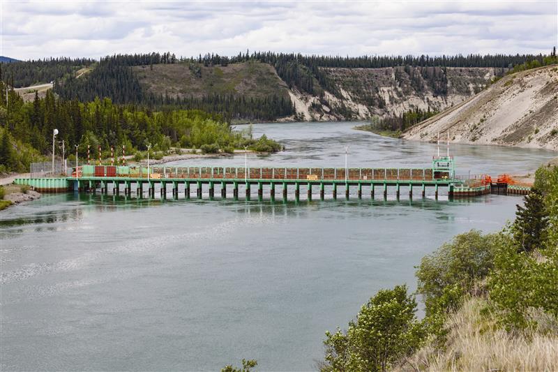 La structure de contrôle Lewes vert et rouge vif, sur le fleuve Yukon, près de Whitehorse, sous un ciel nuageux estival.