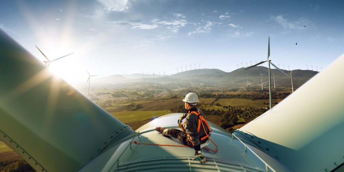 Worker sits atop wind turbine.