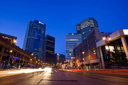 Downtown Winnipeg at night, traffic lights illuminate the road