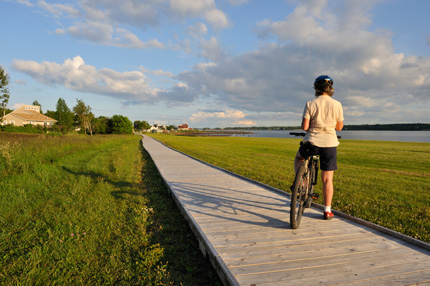 A woman with her bicycle along the boardwalk at dusk