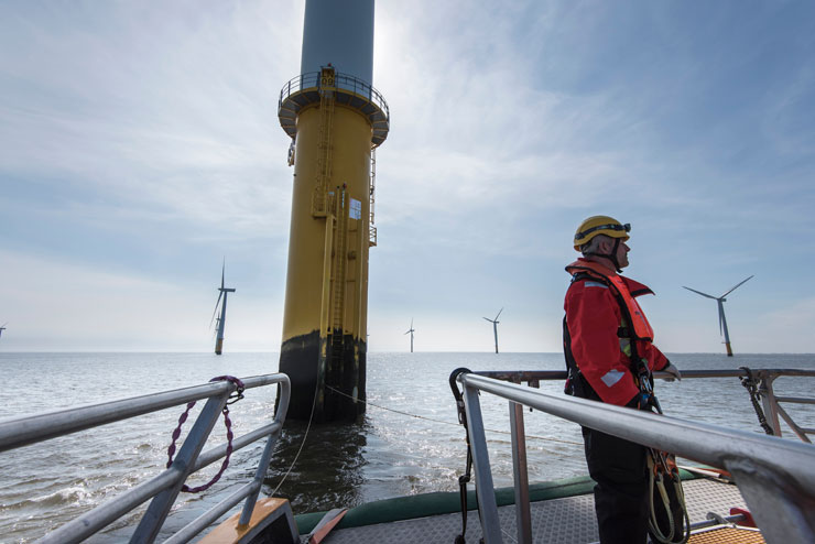 Ingénieur se préparant à escalader une éolienne parmi d’autres en mer