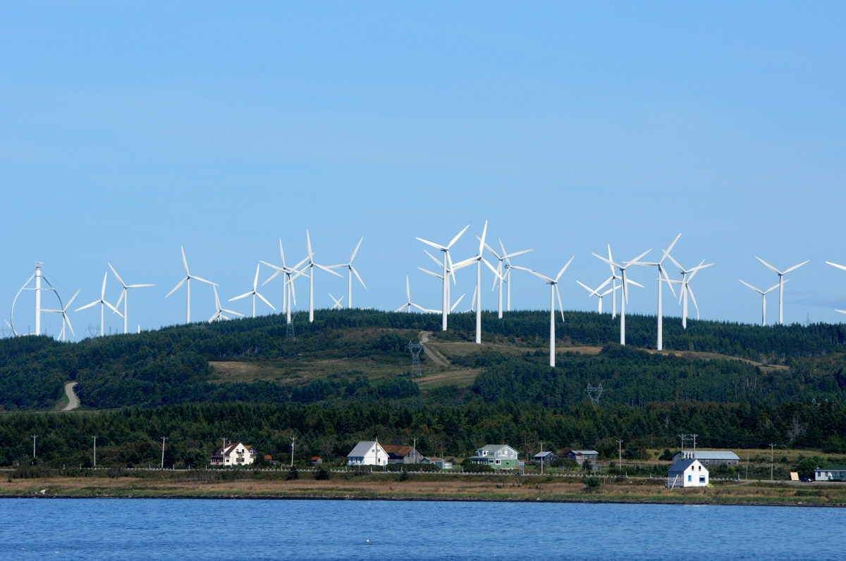 Wind turbines on hillside above ocean in Gaspesie, Quebec.