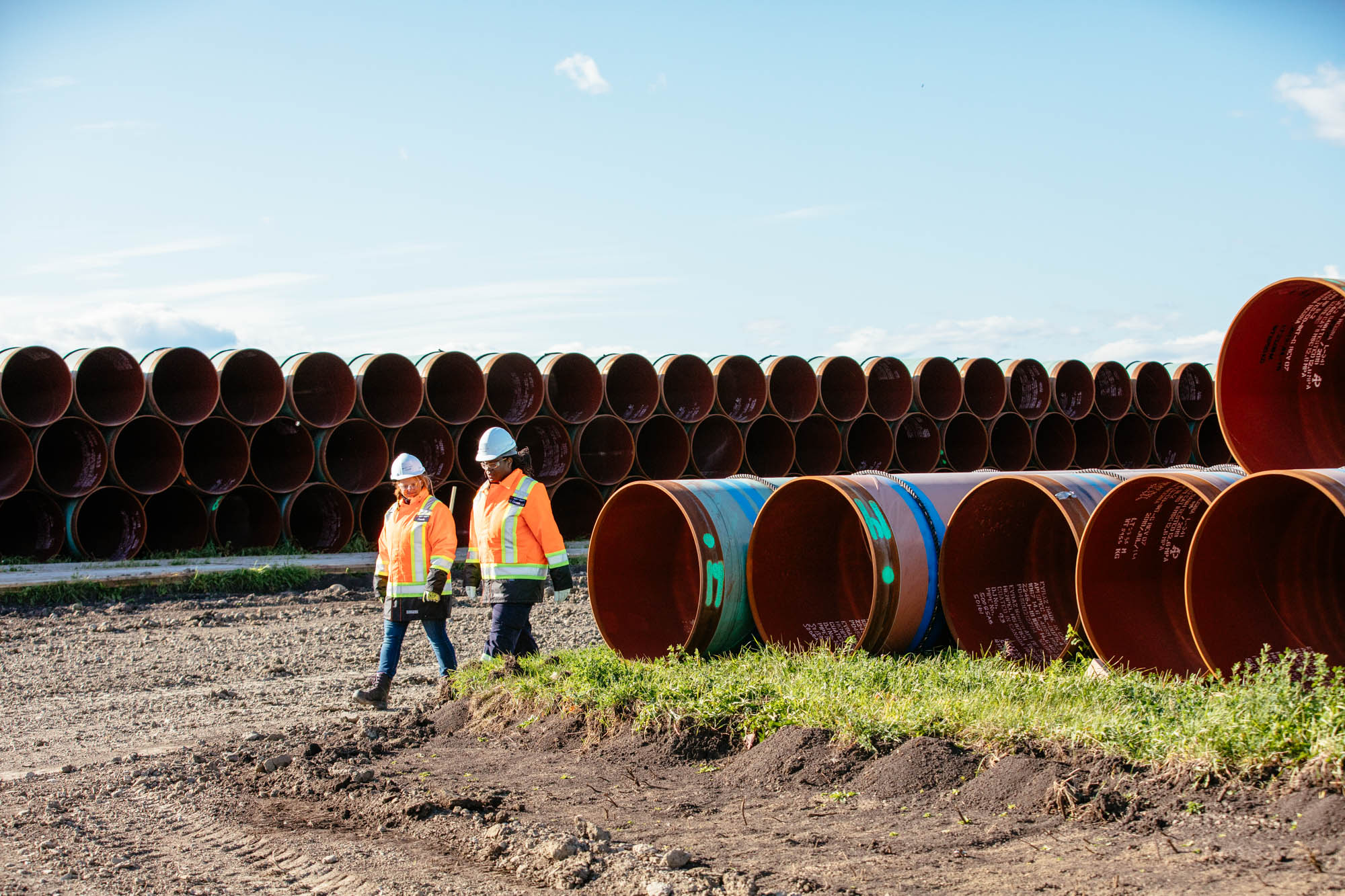 Two CER inspection officers walking through construction site with rows of unused pipes.