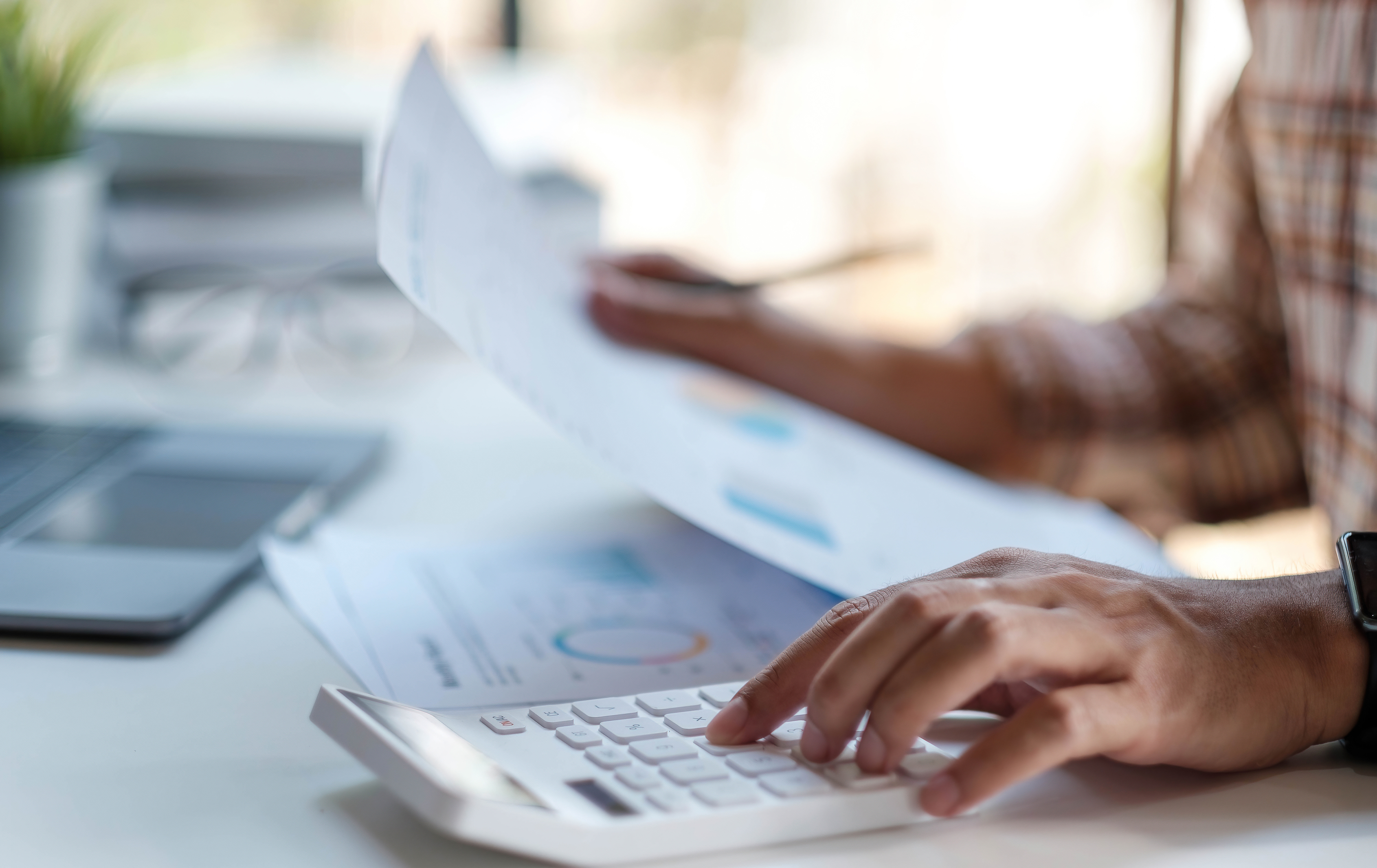 Accountant working on calculator to calculate business data.