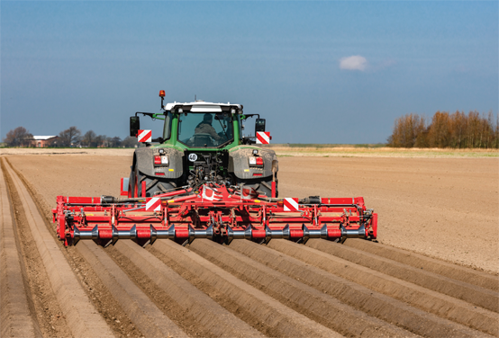 Tracteur avec disqueuse dans un champ de culture de pommes de terre